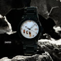 Black wristwatch with unique face design on a rocky surface, brand 'Zayed' visible.